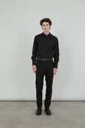 Man wearing a classic black trousers in virgin wool, combined with a classic black shirt and a black leather belt. 