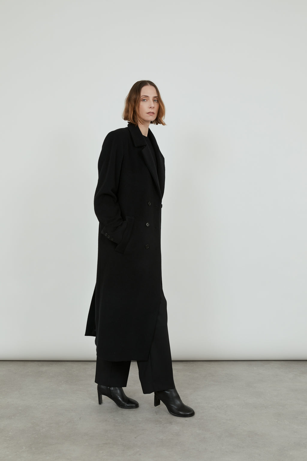 A person wearing a black cashmere Achilles overcoat.