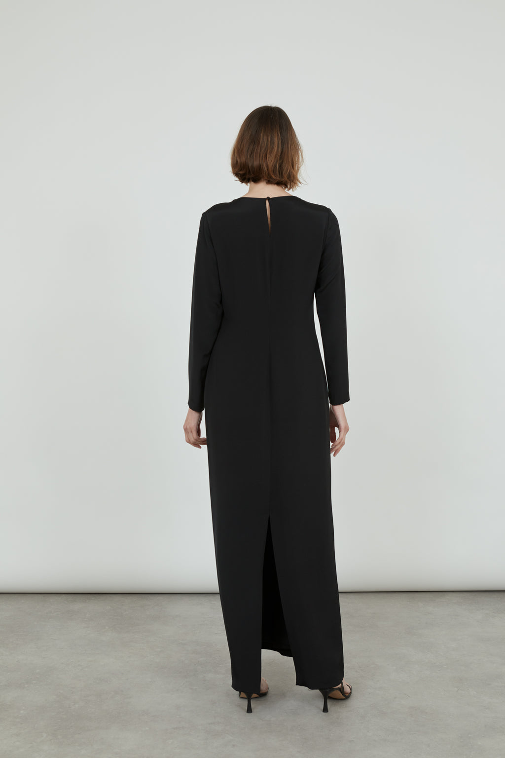 Woman wearing a black Abelun dress in crepe silk, view from the back.