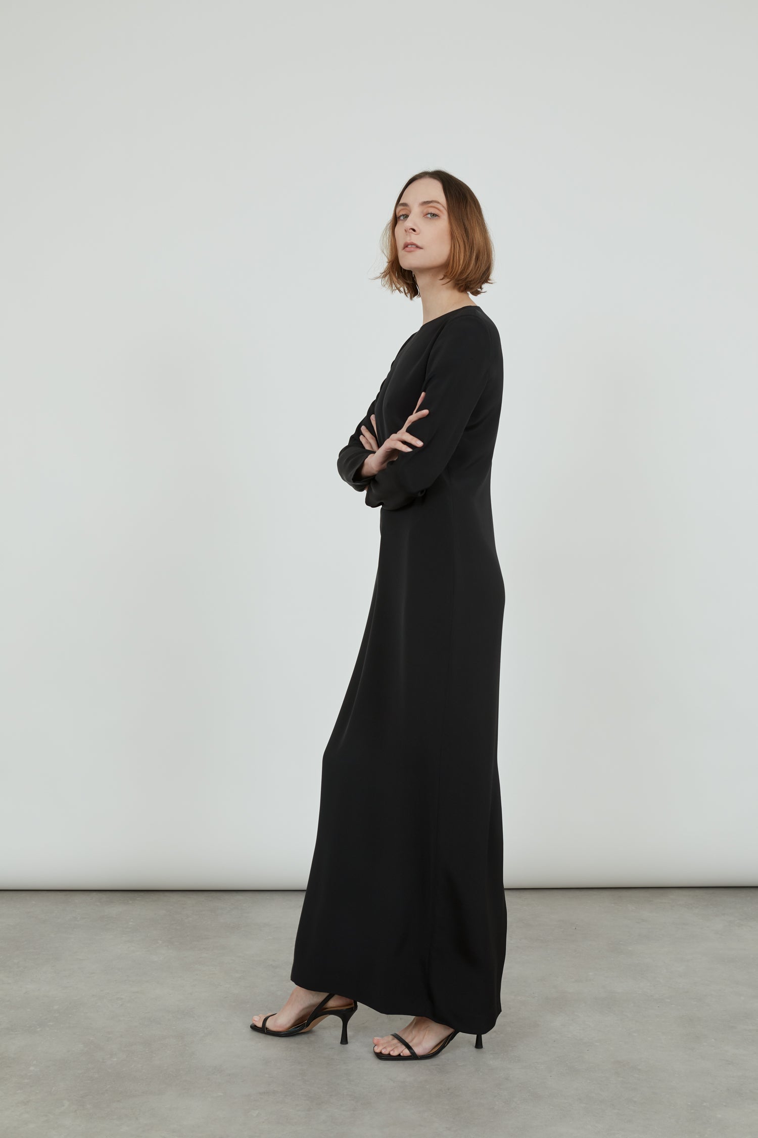 black longsleeve maxi dress in crepe silk, standing sideways