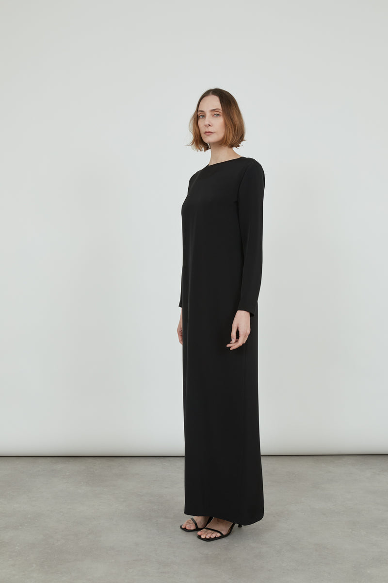 Woman wearing a black Abelun dress in crepe silk, standing sideways.