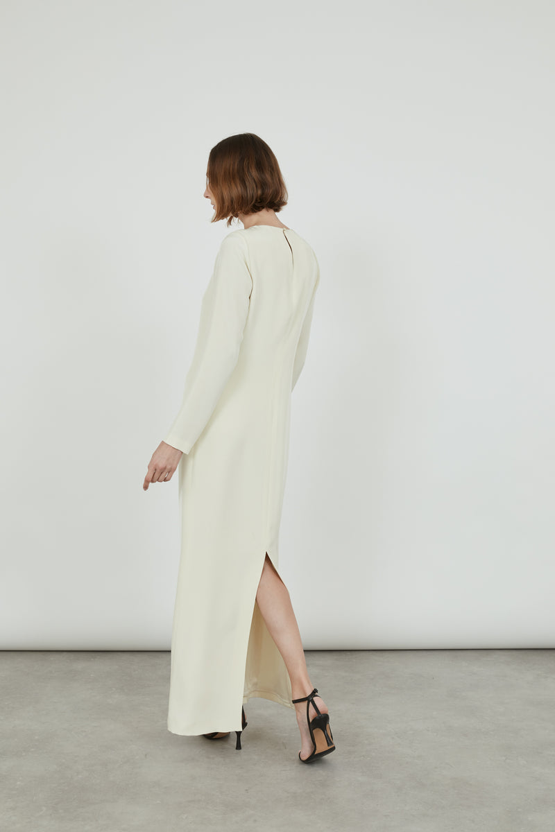 Woman wearing an offwhite Abelun dress in crepe silk, view from the back.
