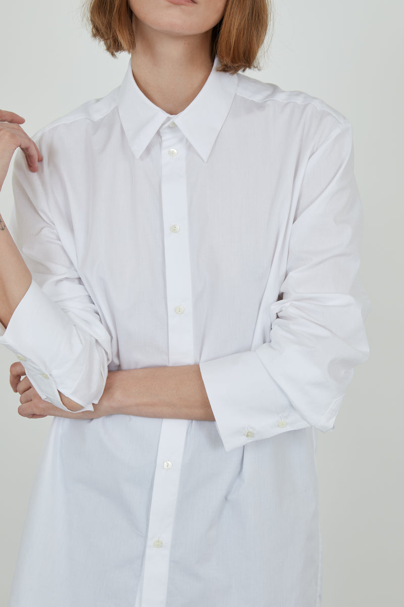 Person wearing a classic white Adam shirt in cotton poplin. 
