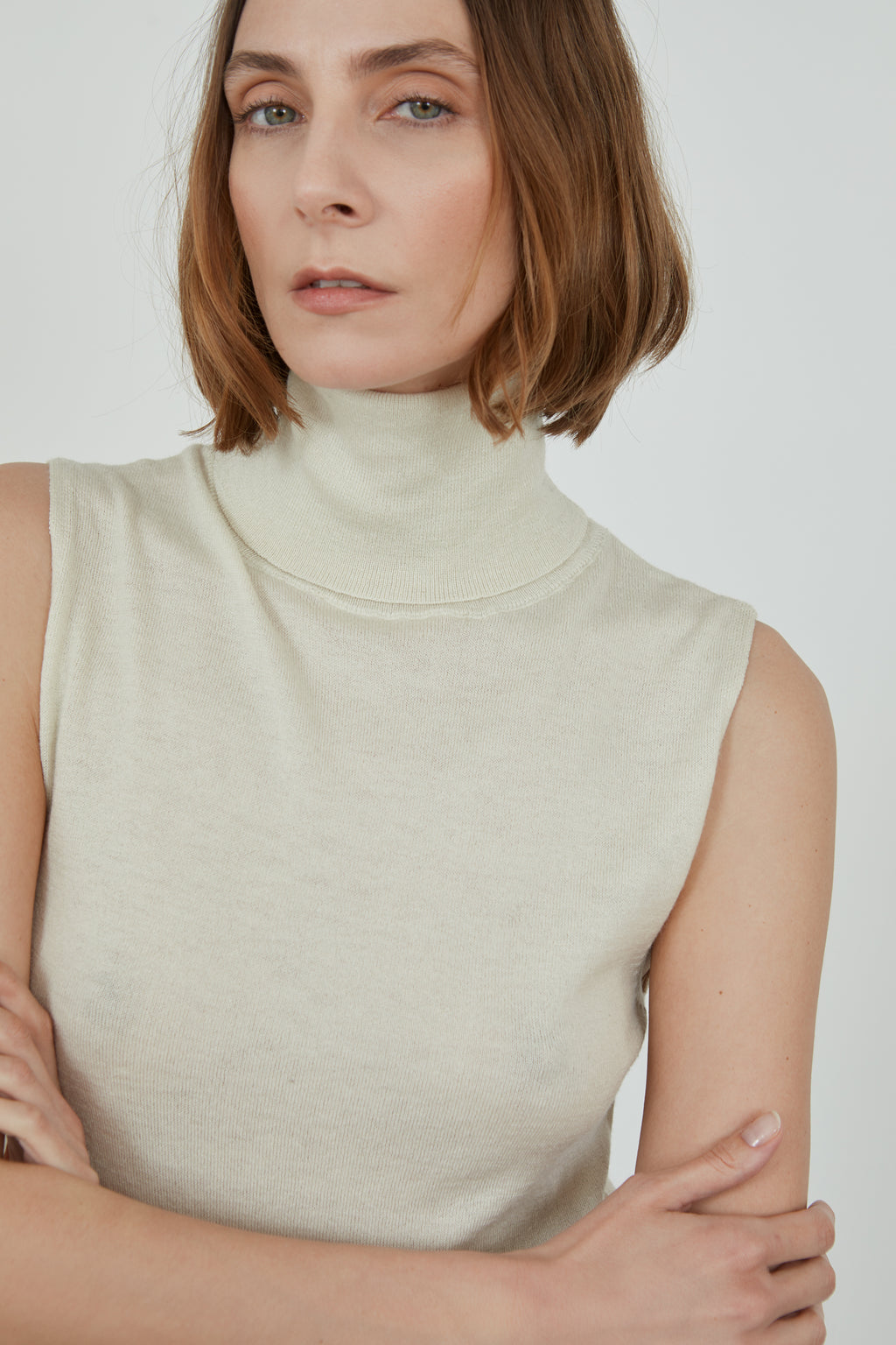 Woman wearing a sleeveless offwhite Deborah knitted top in merino wool, detailed view.