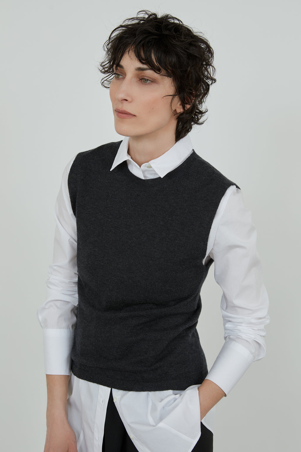 Detailed view of Emma knitted top in Dark Grey over a white shirt with black tailored trousers. 