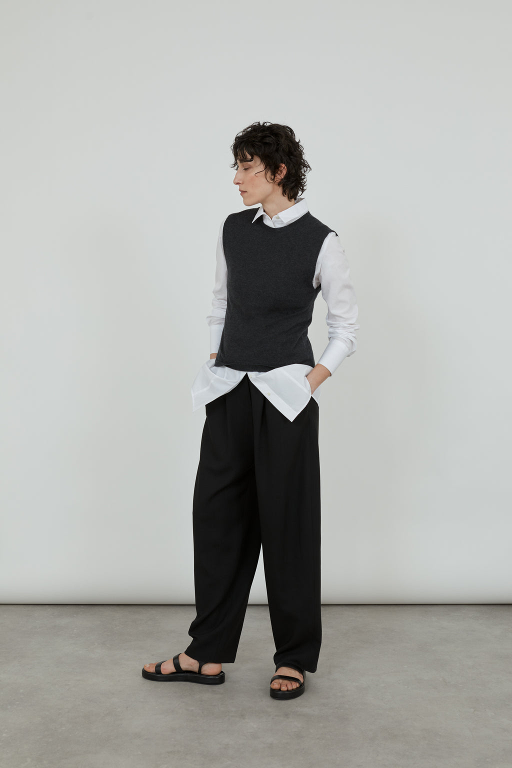 Emma knitted top in dark grey over a white classic shirt and black pants.