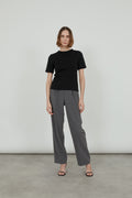 Woman is wearing a black T-shirt and grey trousers.