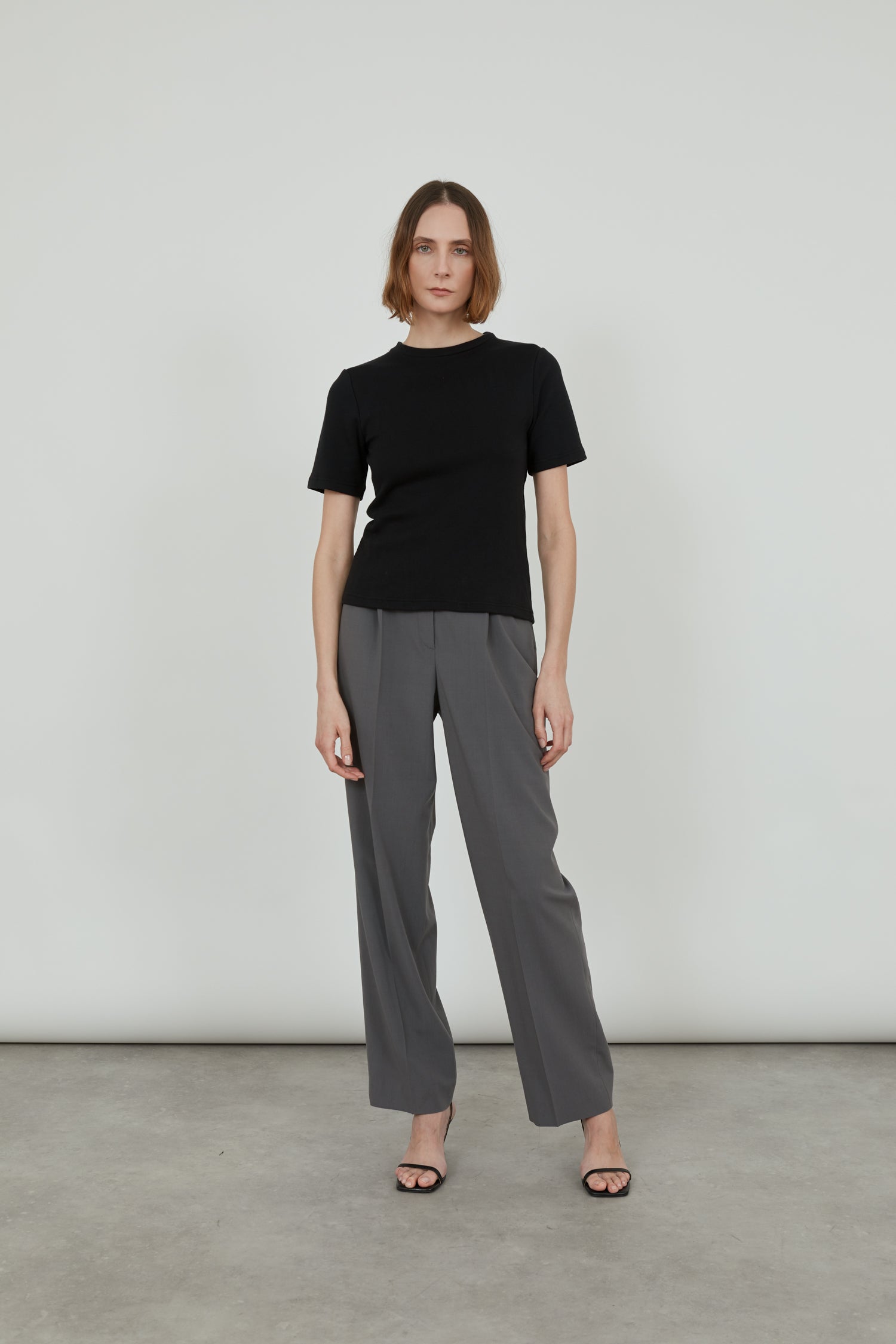 Woman is wearing a black T-shirt and grey trousers.