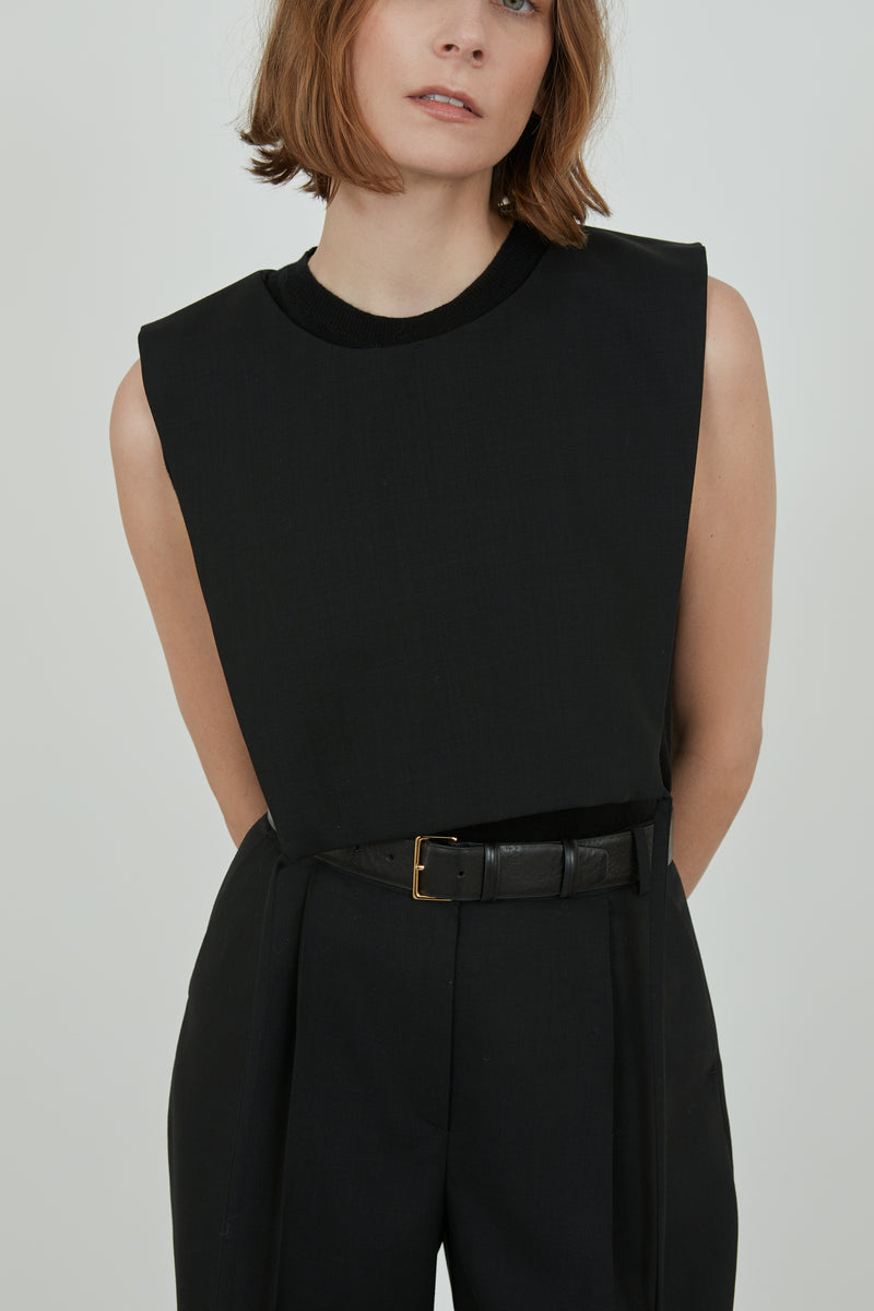 Woman wearing the black Mireille top over a black wool top with classic black pants and a black leather belt. 