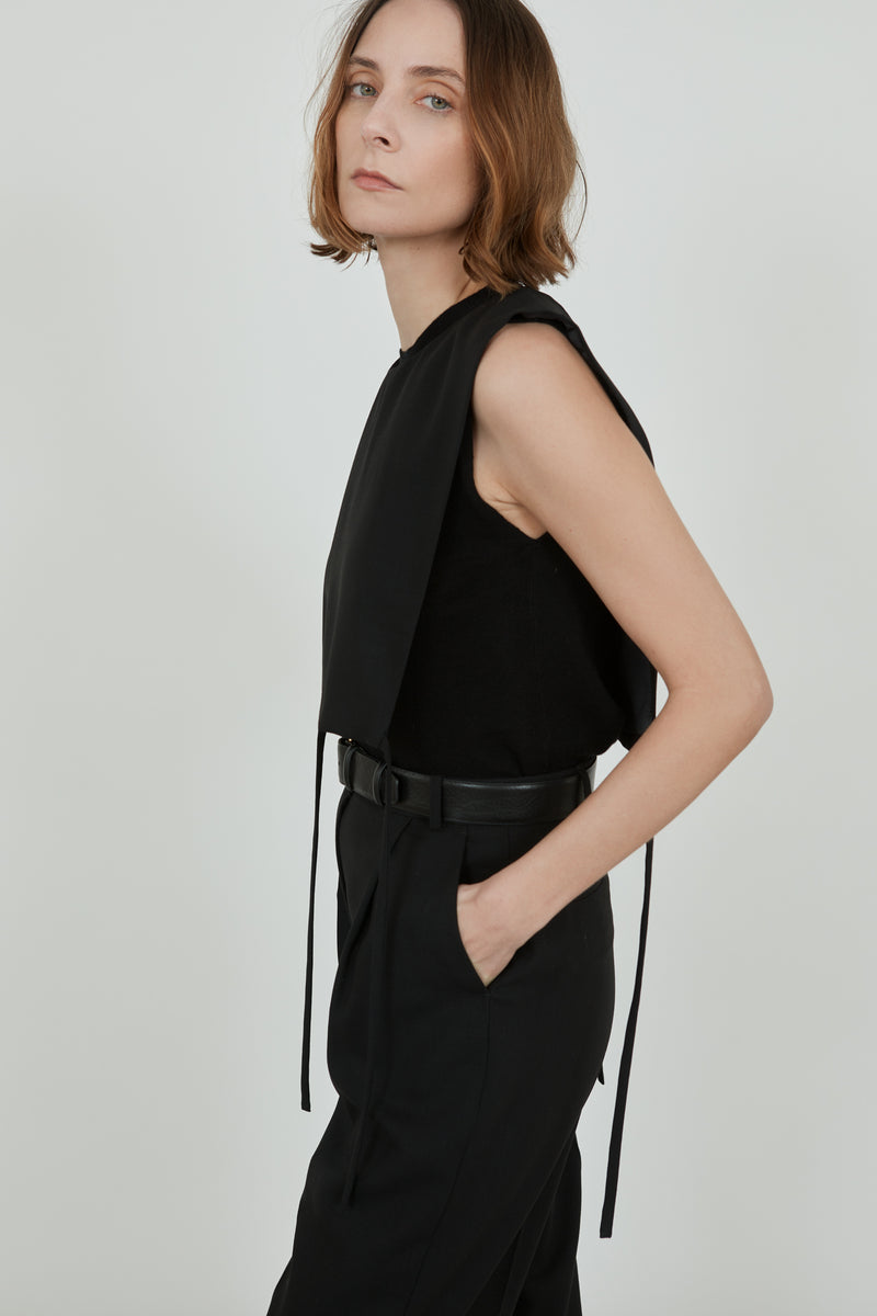 Woman wearing the black Mireille top over a black wool top with classic black pants and a black leather belt. 